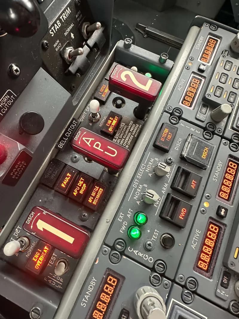 B737 NG cockpit control stand showing the engine and APU fire handles, stabilizer trim switches and radio tuning panels